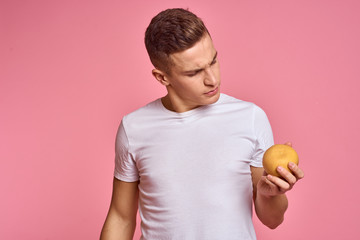 the man with interest looks at the orange in his hand