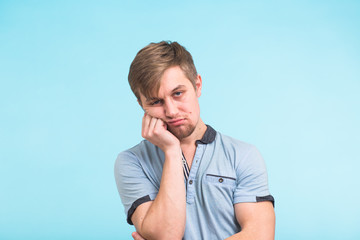 portrait of young bored man on blue background