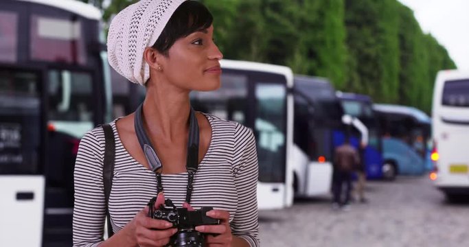 African-American female on vacation looks at photos she took while out sightseeing, Attractive young black girl with a camera photographs her surroundings outside her travel bus, 4k