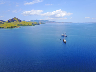 Aerial view of beautiful scenery at Flores island with tourist yatch, turqouise and dark blue sea.