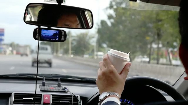 Man driving car while drinking coffee dangerously