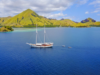 Aerial view of beautiful scenery at Flores island with tourist yatch, turqouise and dark blue sea.