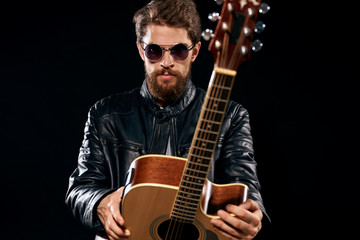 musician with glasses leather jackets and with a guitar in...