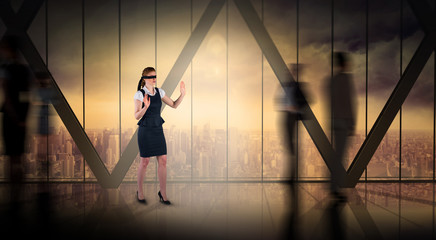 Redhead businesswoman in a blindfold against room with large window looking on city