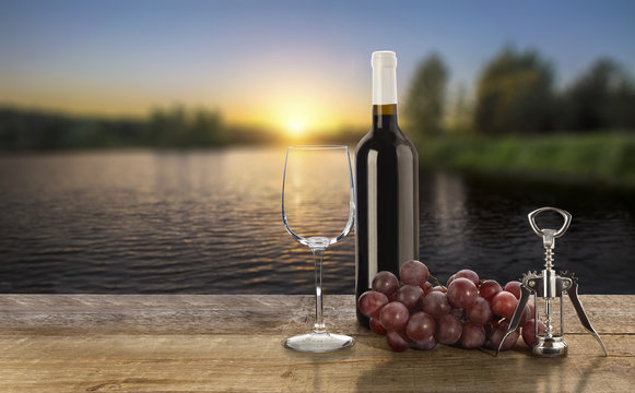 Red wine bottle, empty wine glass, corkscrew and grape on sunset background