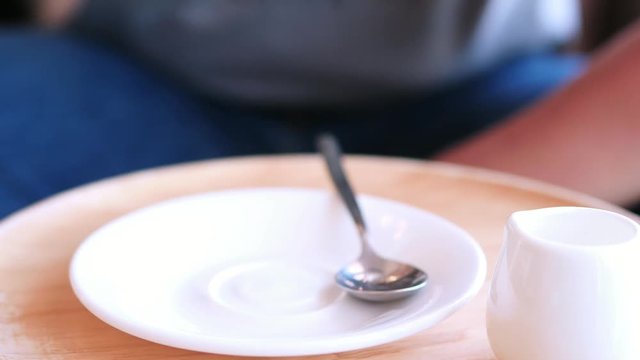 Man drink hot tea cup in the coffee shop close up at cup with white wooden plate and white cup and syrup set and silver tea spoon on table