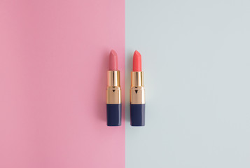 Flat lay minimal concept of creative female cosmetic for pink and orange lipstick on the colorful background with copy space - obrazy, fototapety, plakaty