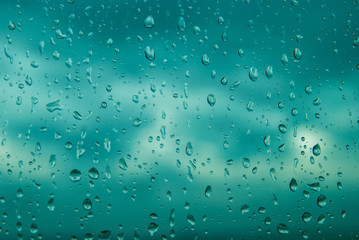 Blue water drops on window glass after rain. Cloud Background