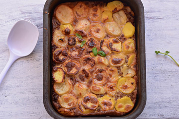 Moussaka, potato-based dish popular in Balkan and Mediterranean cuisines/ Traditional Greek moussaka whit ground beef and potatoes on light wooden table background