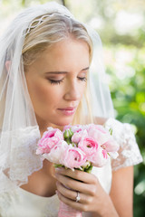 Happy bride in a veil smelling her rose bouquet