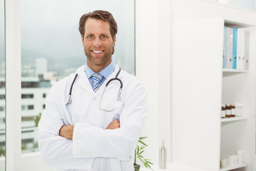 Smiling doctor with arms crossed in medical office