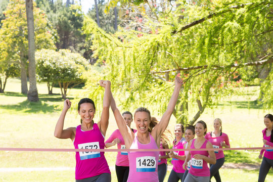 Smiling women running for breast cancer awareness