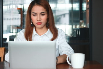 Fototapeta na wymiar Attractive young Asian business woman with laptop working in modern office.