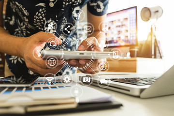 businessman or Designer using smart phone with laptop and digital tablet computer and document on desk in modern office with virtual interface graphic icons network diagram

