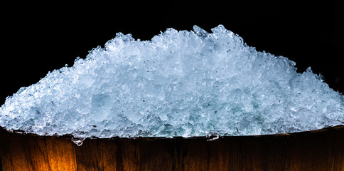 Pile of crushed ice cubes in wood bucket on dark background with copy space. Crushed ice cubes...