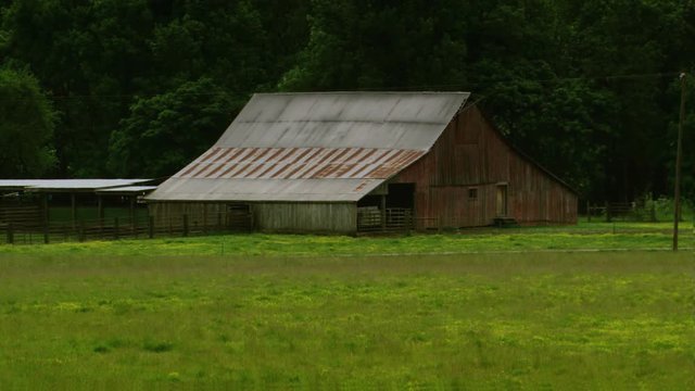 Widening view of old cow barns and pasture