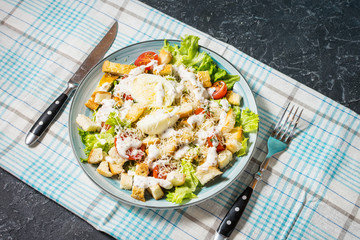 Fresh caesar salad in plate on stone table.