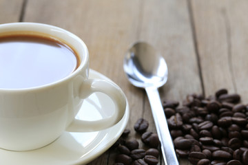 White coffee mug and coffee beans on a vintage wooden table.