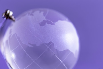 Globe is made of glass on a purple background. Glass globe. Globalization concept
