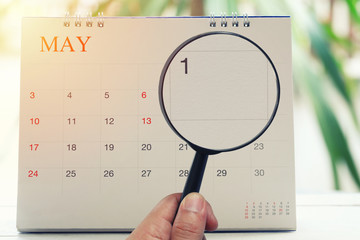 Magnifying glass in hand on calendar you can look first day of month,Focus number one in May.