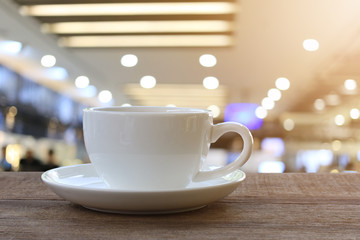 White Coffee cup on wooden table in coffee shop blur background.