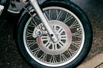 Motorcycle wheel with disk brakes system and metal spokes. Closeup detailed photo of motorbike forks and tire. Different parts of two-wheeled vehicle.  Transportation. Modern driving technologies.