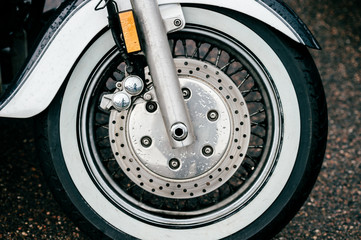Motorcycle wheel with disk brakes system and metal spokes. Closeup detailed photo of motorbike forks and tire. Different parts of two-wheeled vehicle.  Transportation. Modern driving technologies.