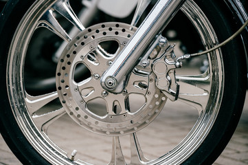 Motorcycle wheel with disk brakes system and metal spokes. Closeup detailed photo of motorbike forks and tire. Different parts of two-wheeled vehicle.  Transportation. Modern driving technologies.