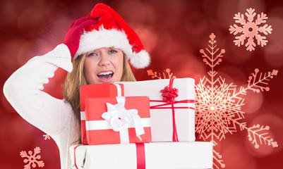 Festive blonde holding pile of gifts against red snow flake pattern design