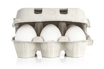 Six white chicken eggs in a paper grey crate isolated on white background front view.