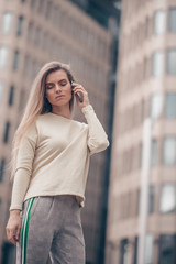 Fototapeta premium Beautiful woman is having a business conversation by mobile phone near modern office building