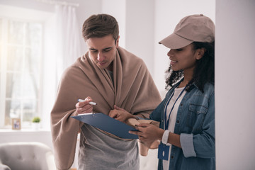 Delivery confirmation. Good looking young man holding a pen while putting his signature on the delivery documents
