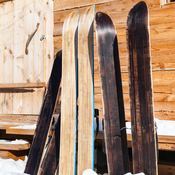 wide forest skis near door of wooden cottage