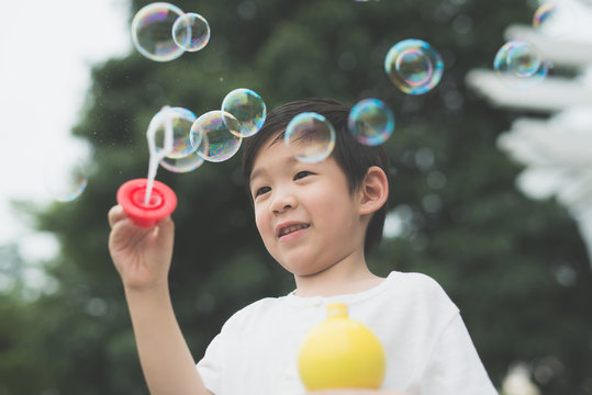 asian child is blowing a soap bubbles