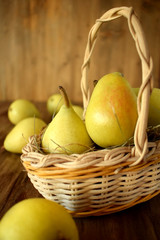 Little pears in a wicker basket on wooden background