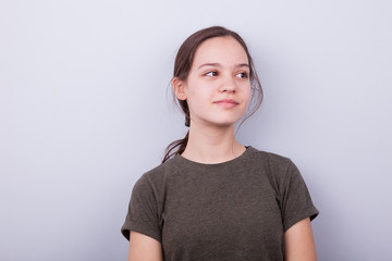Portrait of cute teenage girl on gray background in studio