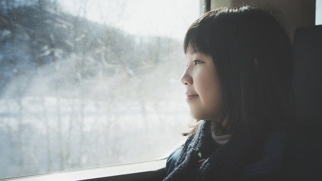asian girl looking through window. She travels on a train