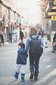 Asian mother and her son walking in city
