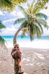 young woman with hat at the beach with palm tree Seychelles white tropical island