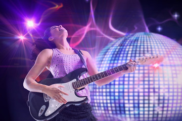 Pretty girl playing guitar against digitally generated shiny disco ball