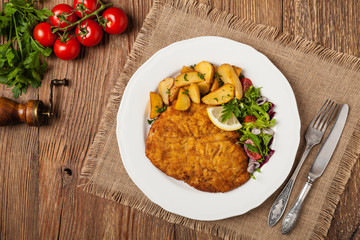 Chicken schnitzel, served with roasted potatoes and salad.