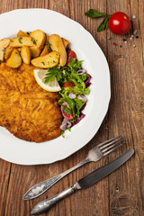 Chicken schnitzel, served with roasted potatoes and salad.