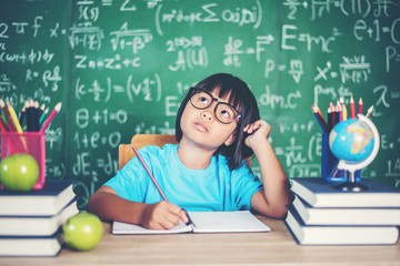 Thoughtful little girl with book near a school board