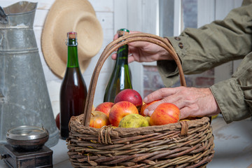 man with bottle of cider and basket of apples, close-up