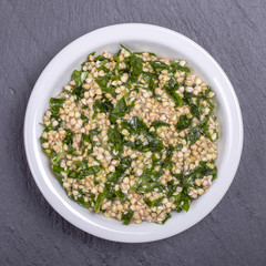 Green buckwheat together with ramson, sesame and honey in white bowl - healthy breakfast food concept, top view