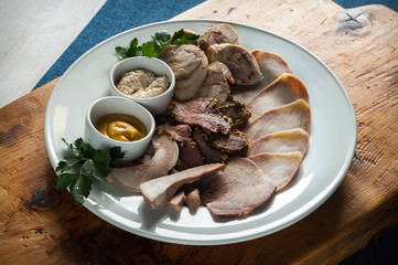 Meat slicing on a large white plate decorated with greenery