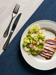 Vegetable salad with meat and sauce on a large white plate