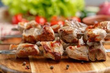 Appetizing shish kebab from pork cooked on an open fire. Still-life on a wooden background.
