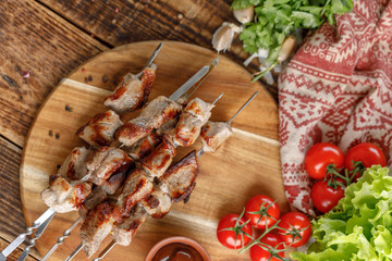 Still life with juicy kebabs laid out on a wooden board. Appetizing meat cooked on an open fire.