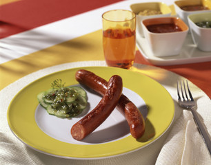 Käsewürstchen mit Gürkchen auf Teller
